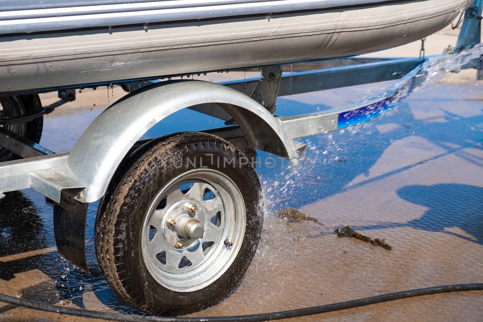 A man washes a rubber hose boat after going to sea. Drops of water scatter from the boat.