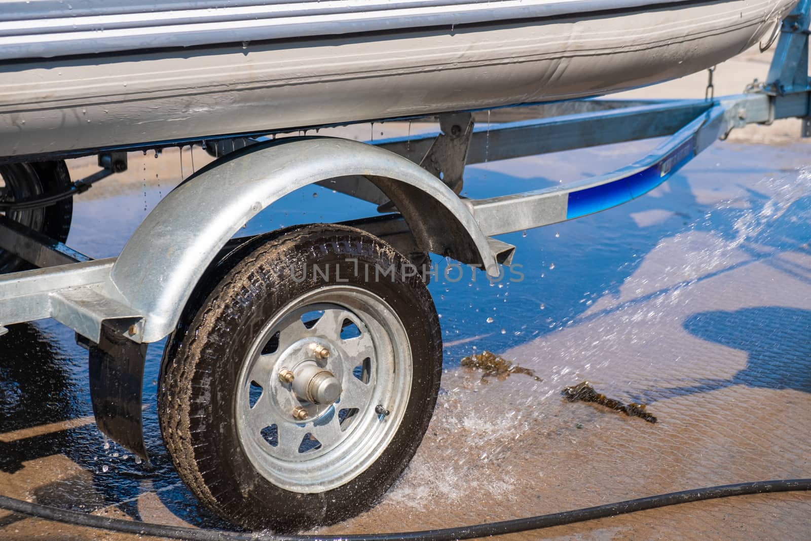 A man washes a rubber hose boat after going to sea. Drops of water scatter from the boat. by rdv27