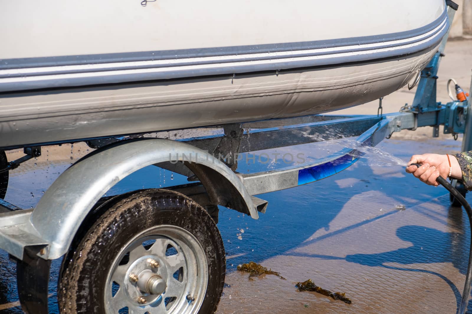 A man washes a rubber hose boat after going to sea. Drops of water scatter from the boat.