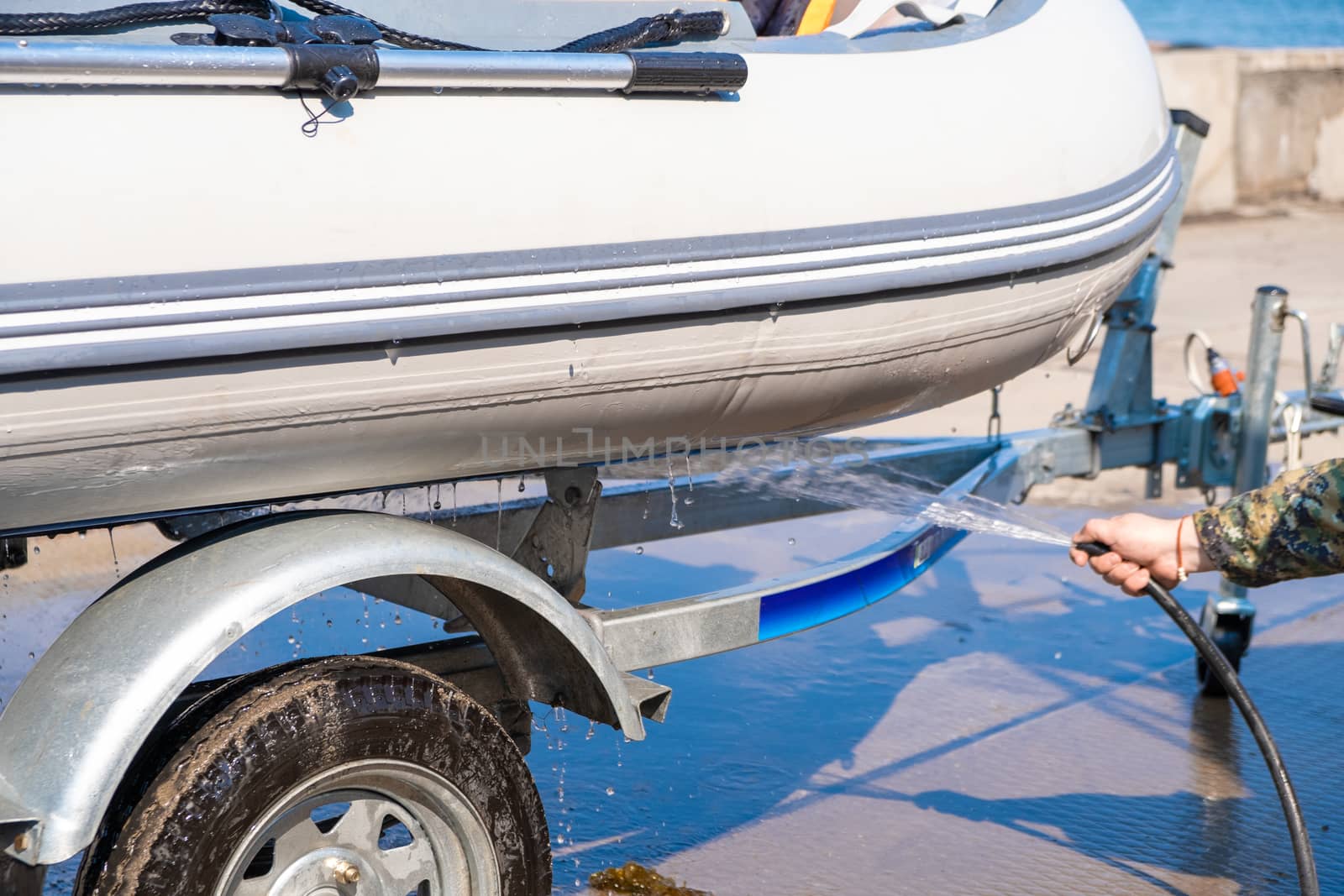 A man washes a rubber hose boat after going to sea. Drops of water scatter from the boat. by rdv27