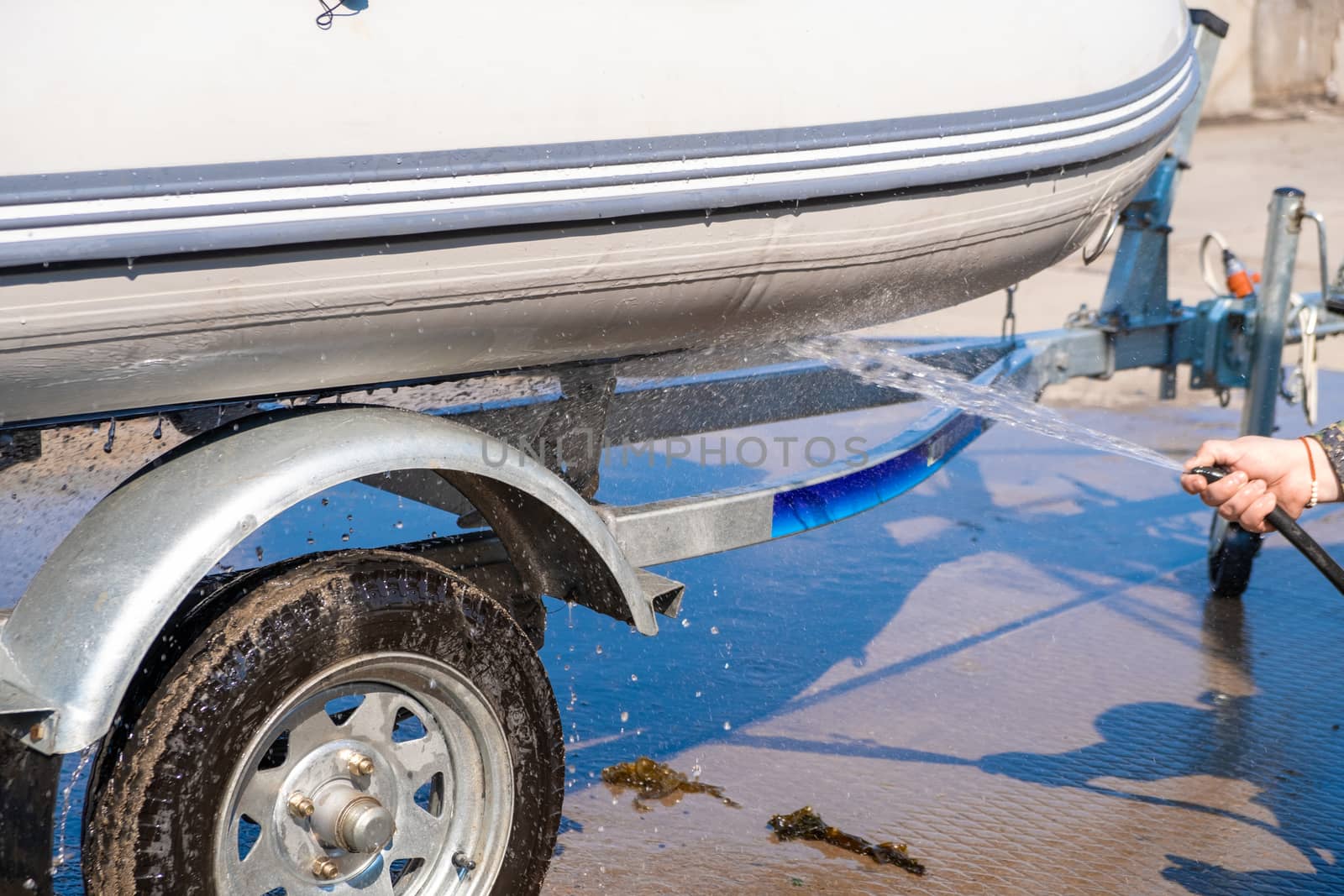 A man washes a rubber hose boat after going to sea. Drops of water scatter from the boat. by rdv27