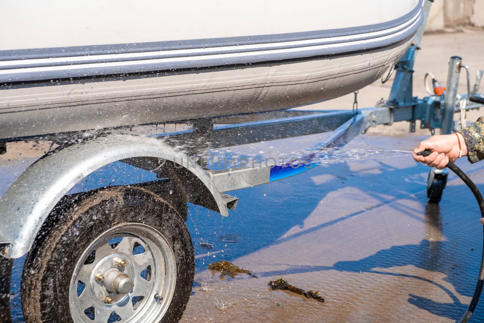 A man washes a rubber hose boat after going to sea. Drops of water scatter from the boat.