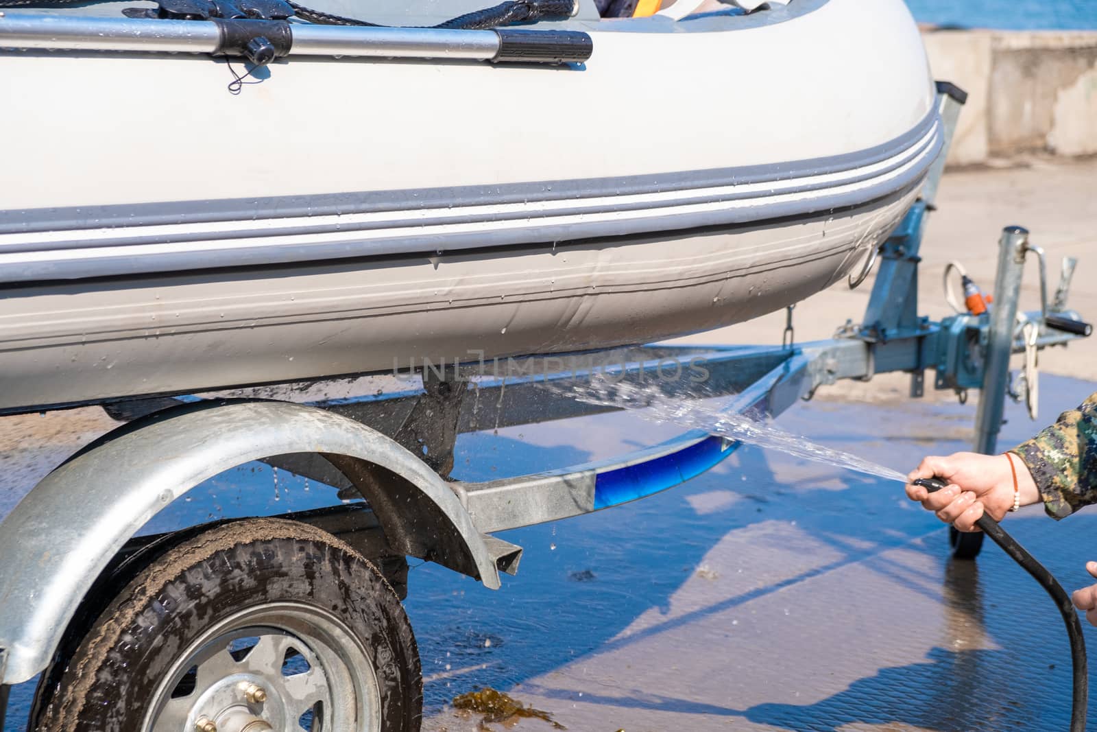 A man washes a rubber hose boat after going to sea. Drops of water scatter from the boat.