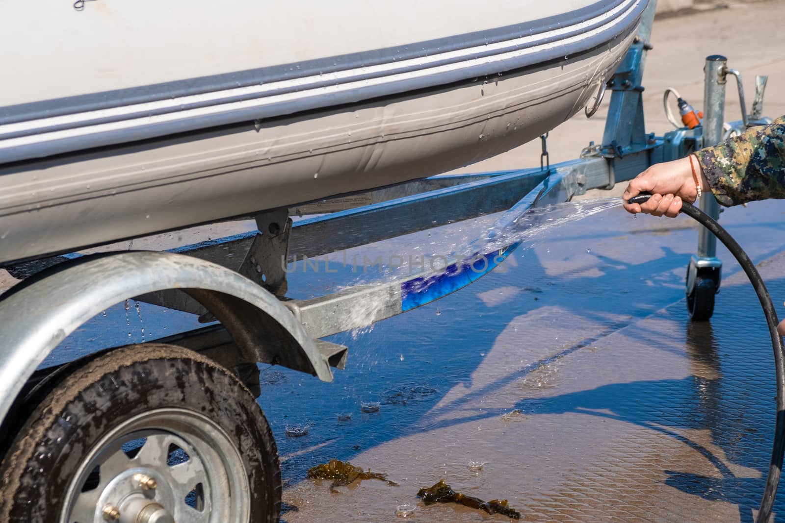 A man washes a rubber hose boat after going to sea. Drops of water scatter from the boat.