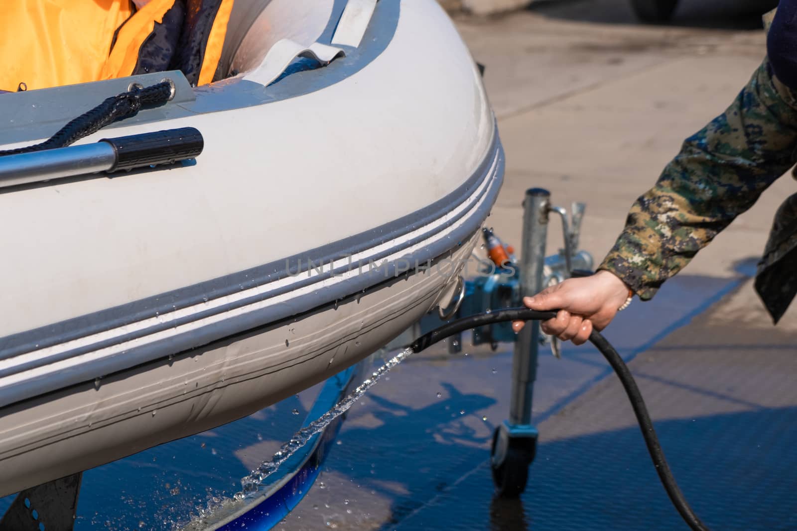 A man washes a rubber hose boat after going to sea. Drops of water scatter from the boat. by rdv27