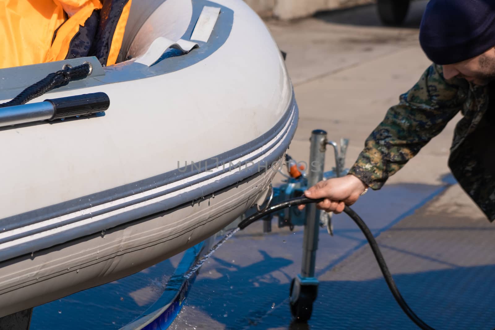 A man washes a rubber hose boat after going to sea. Drops of water scatter from the boat.