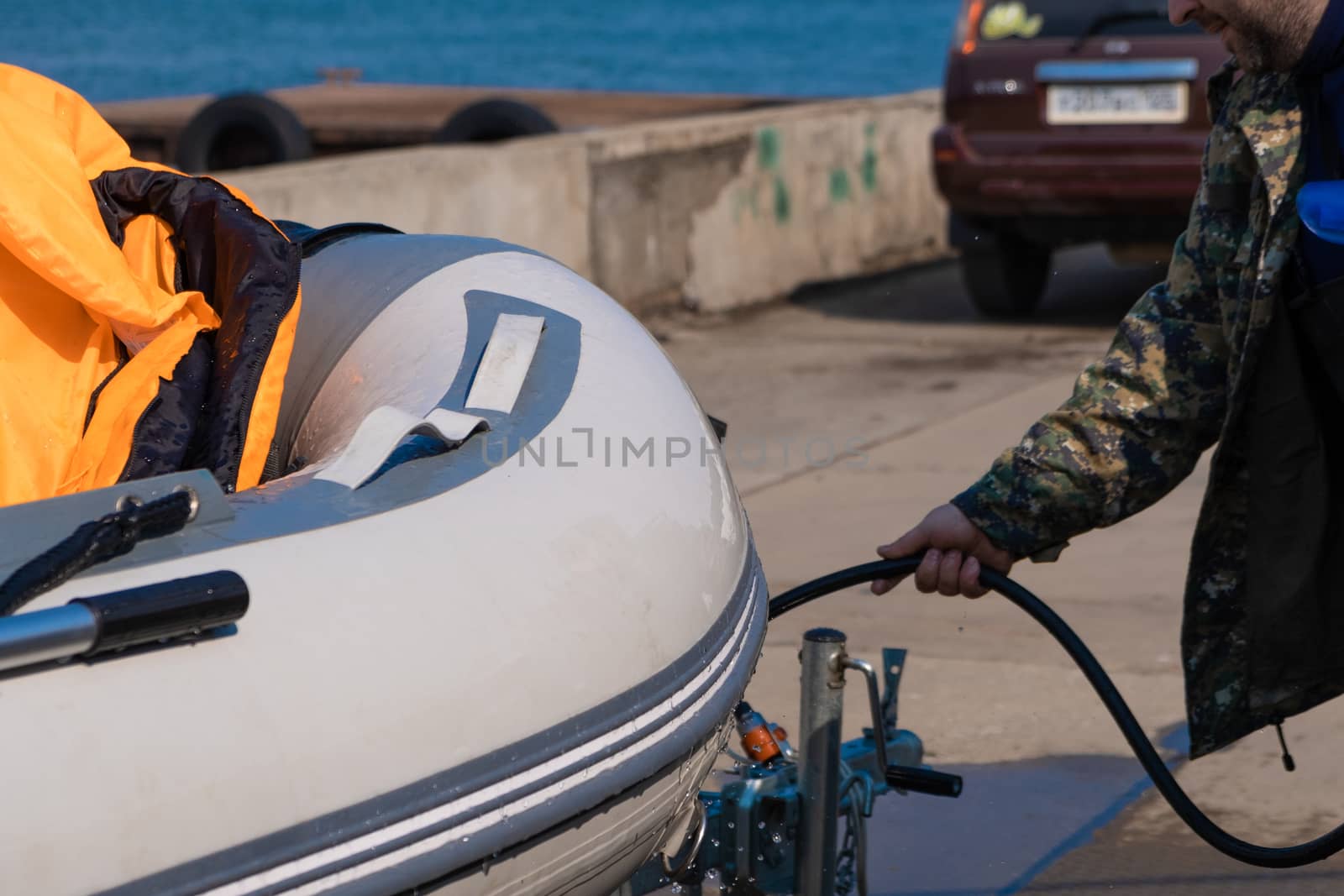 A man washes a rubber hose boat after going to sea. Drops of water scatter from the boat.