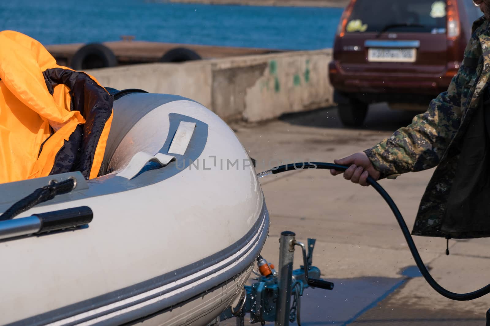 A man washes a rubber hose boat after going to sea. Drops of water scatter from the boat.