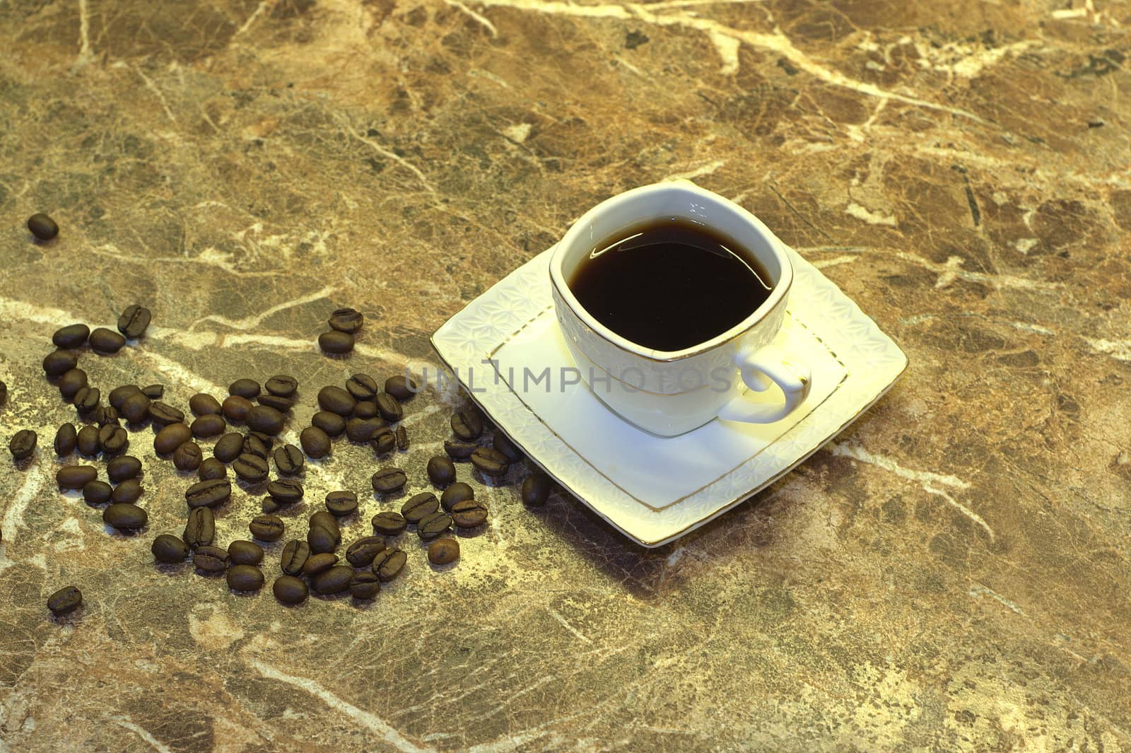 A cup of black coffee and coffee beans lie on a marble table.