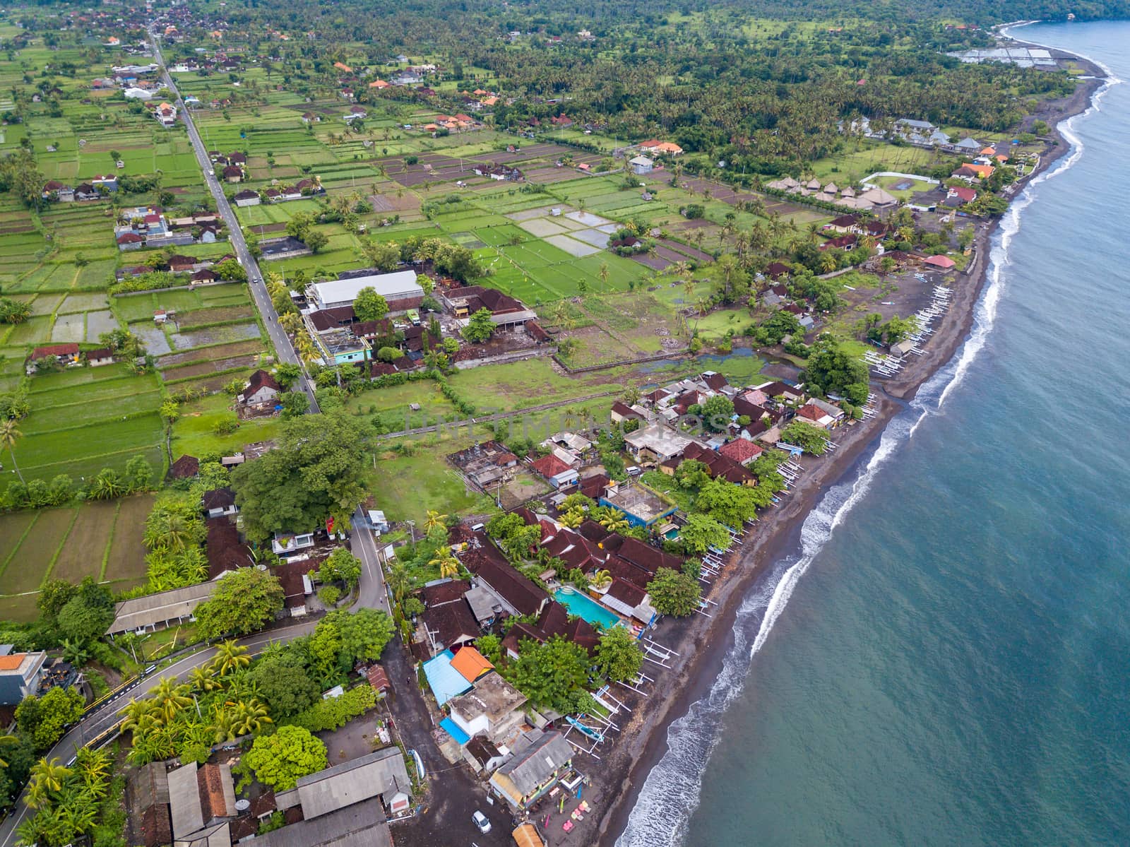 Aerial view of Amed beach in Bali, Indonesia. Traditional fishing boats called jukung on the black sand beach.