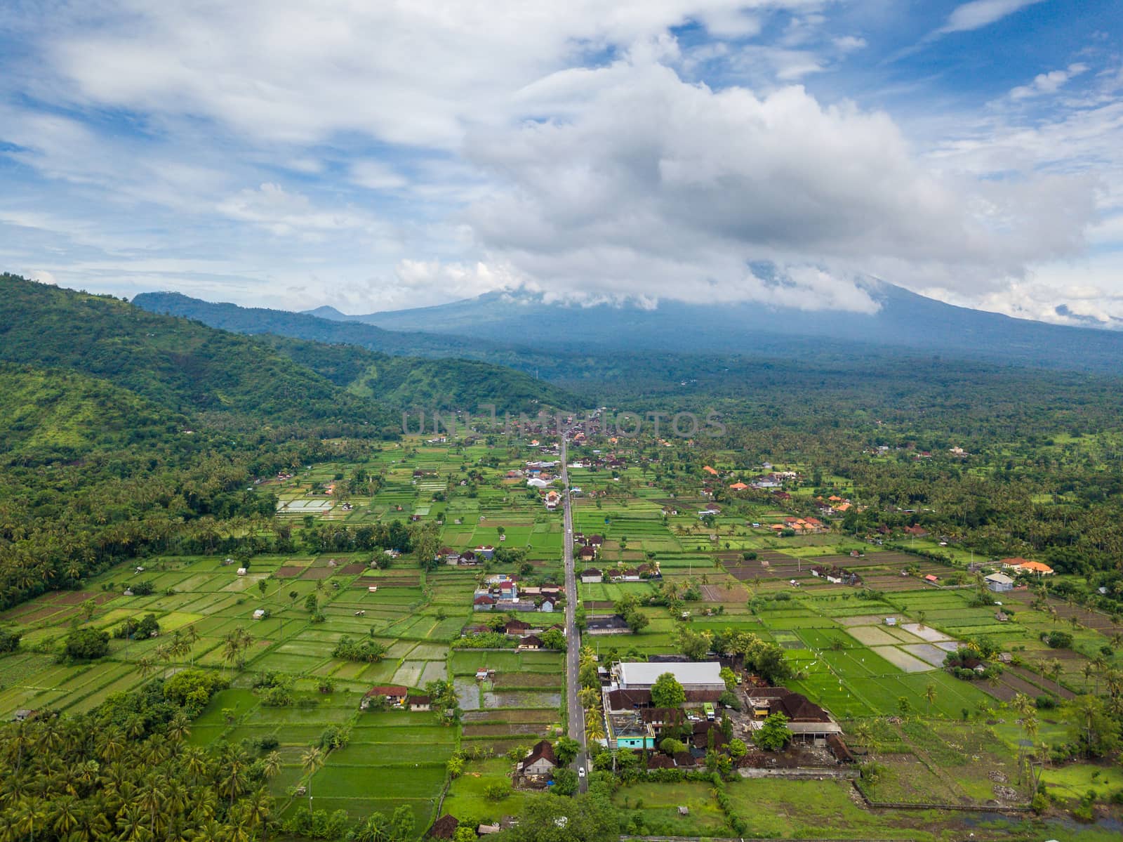 Aerial view of Amed in Bali, Indonesia. Mount Agung volcano in the background, partially covered by clouds.