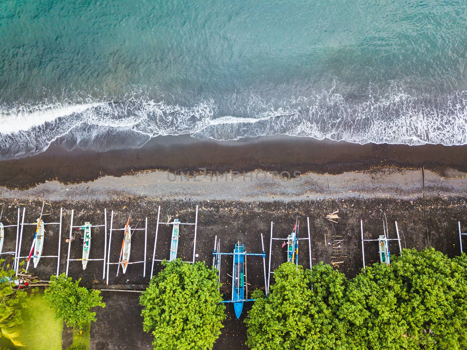 Top down aerial view of traditional Indonesian fishing boats called jukung on black sand beach. In Amed, Bali, Indonesia.    