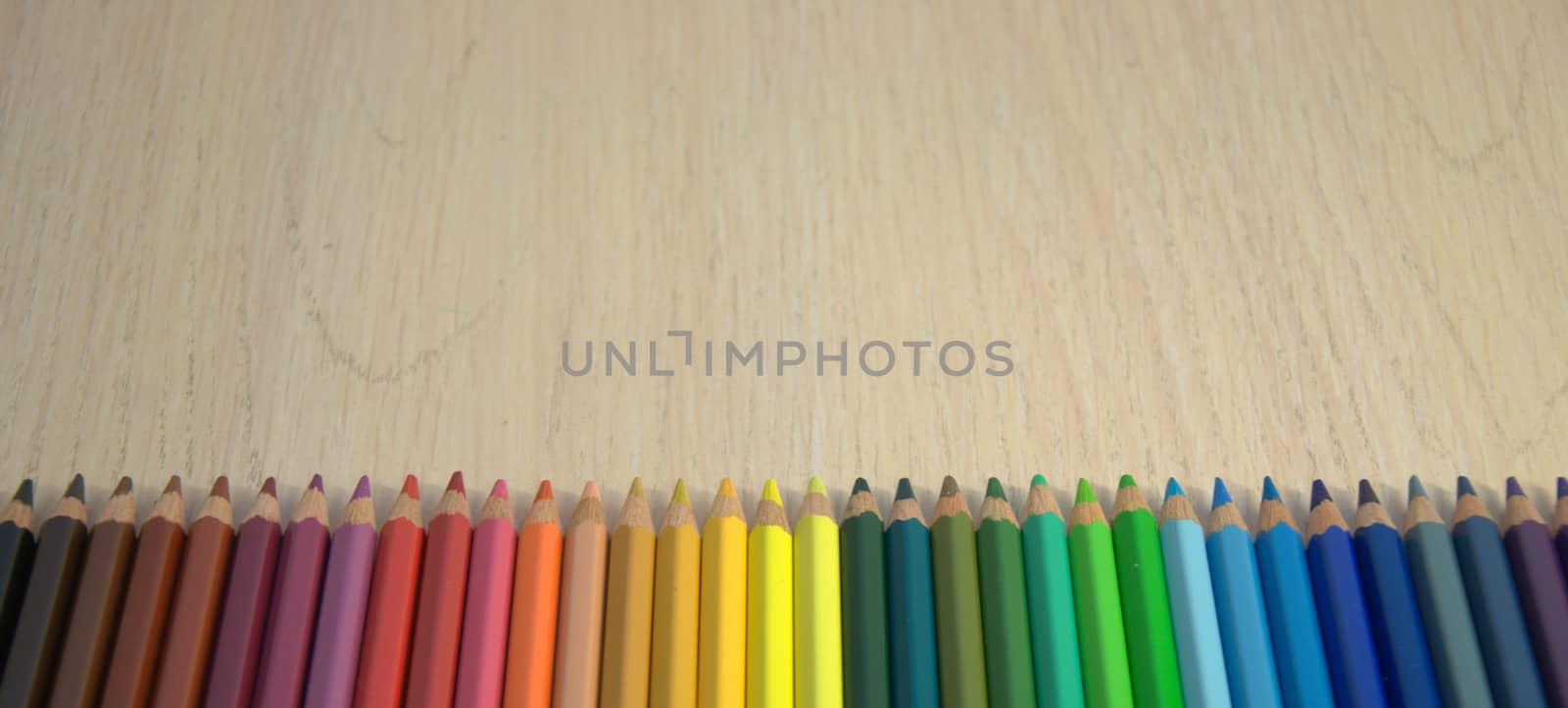 A set of colored pencils laid out in a row on the color spectrum. Close up.
