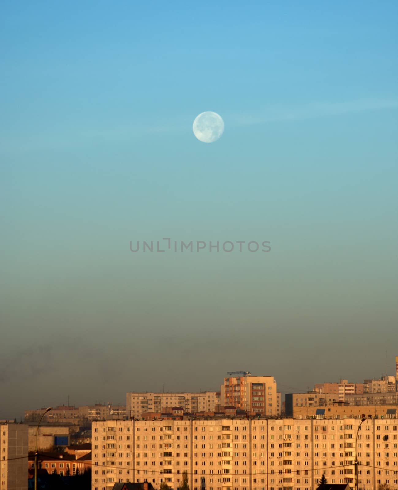 The disk of the moon over the city, early in the morning at dawn. Snapshot with natural light.