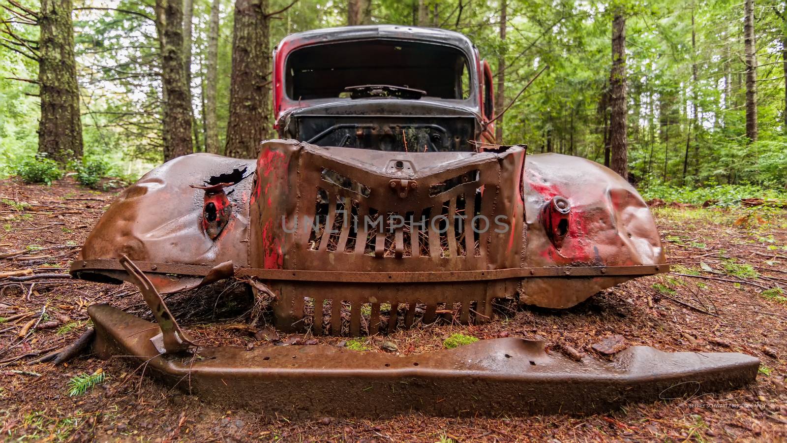 An abandoned antique vehicle rusts in a Northern California forest.