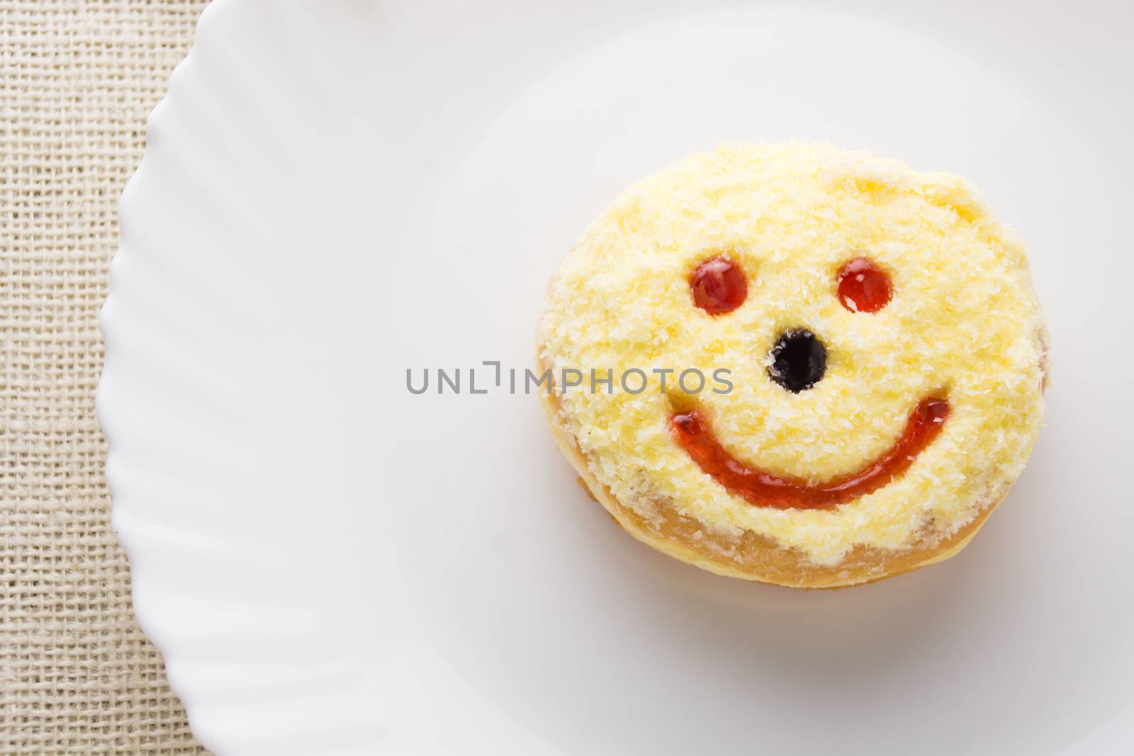 Smiley donut on a white plate, donut with white background