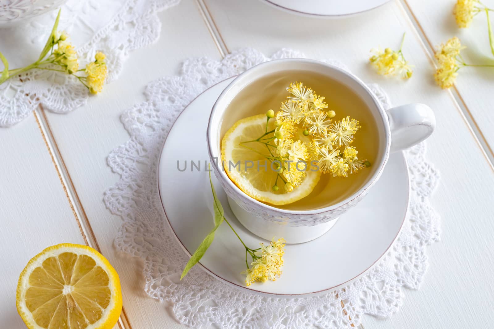 A cup of herbal tea with linden flowers on a white table