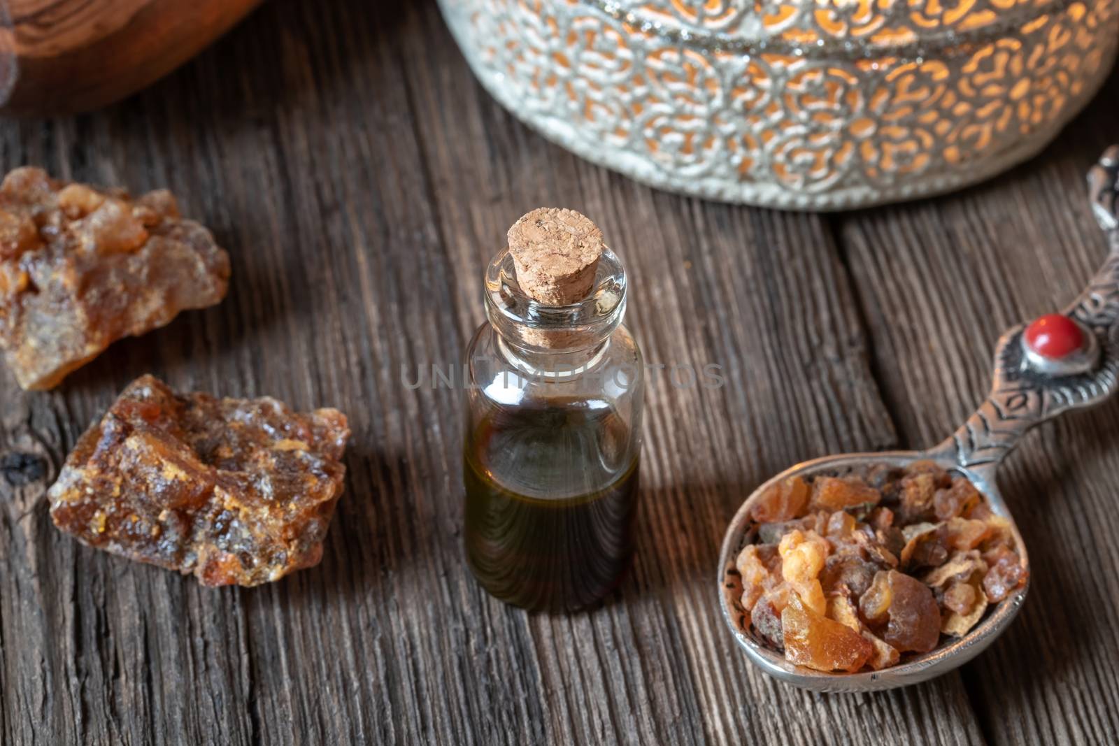 A bottle of essential oil with myrrh resin crystals and an aroma lamp