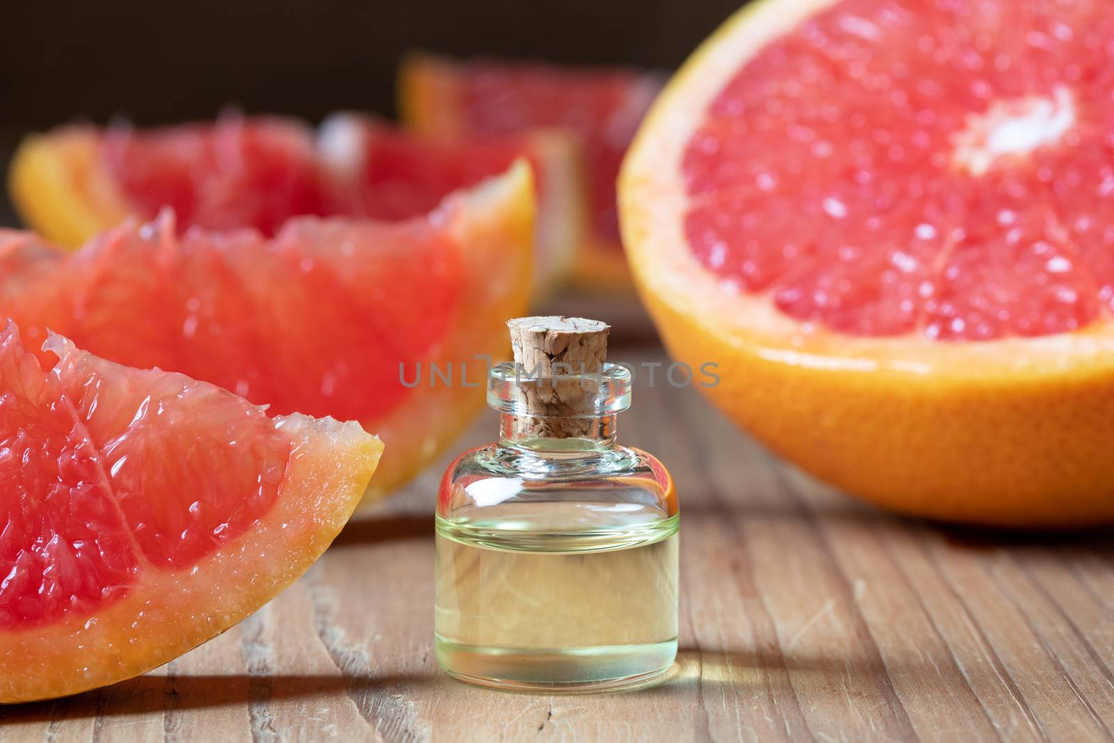 A bottle of citrus essential oil with fresh pink grapefruit