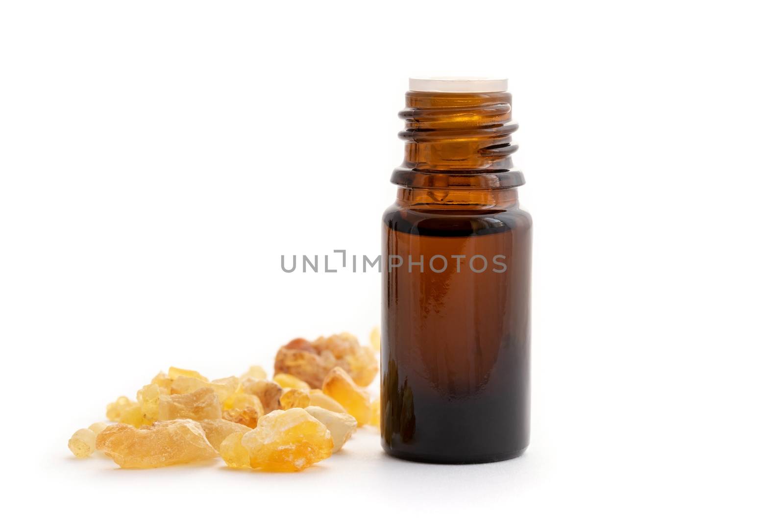 A bottle of essential oil with frankincense resin on a white background