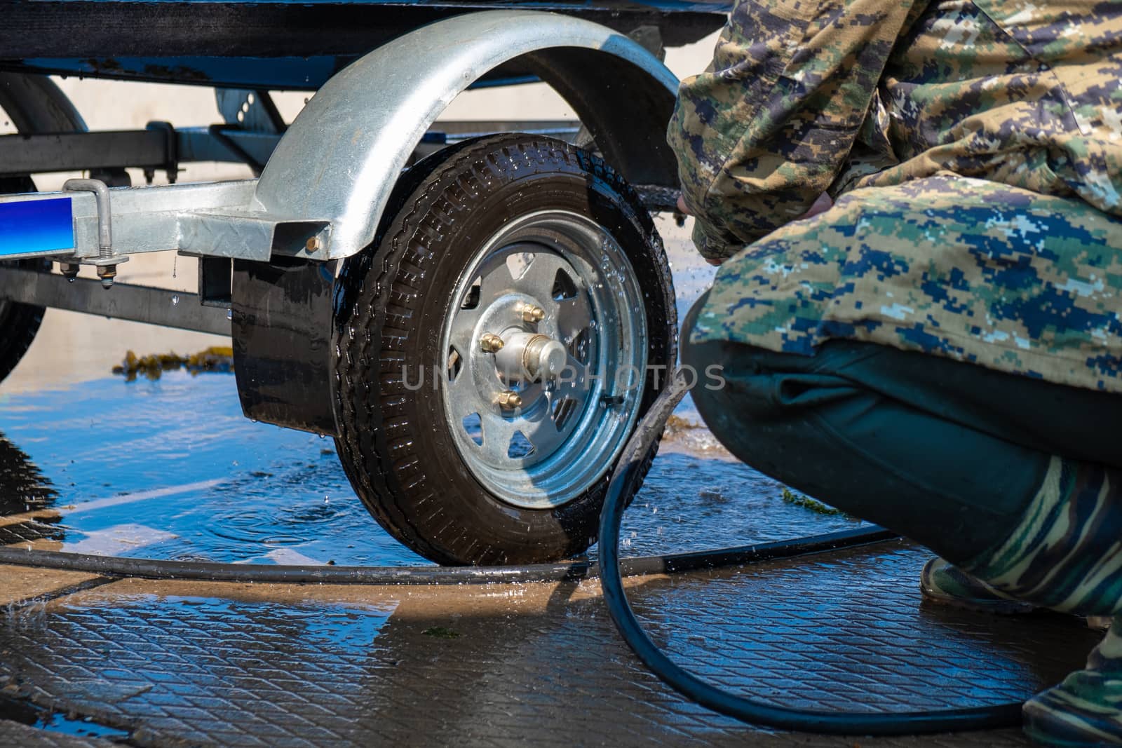 A man washes a rubber hose boat after going to sea. Drops of water scatter from the boat.