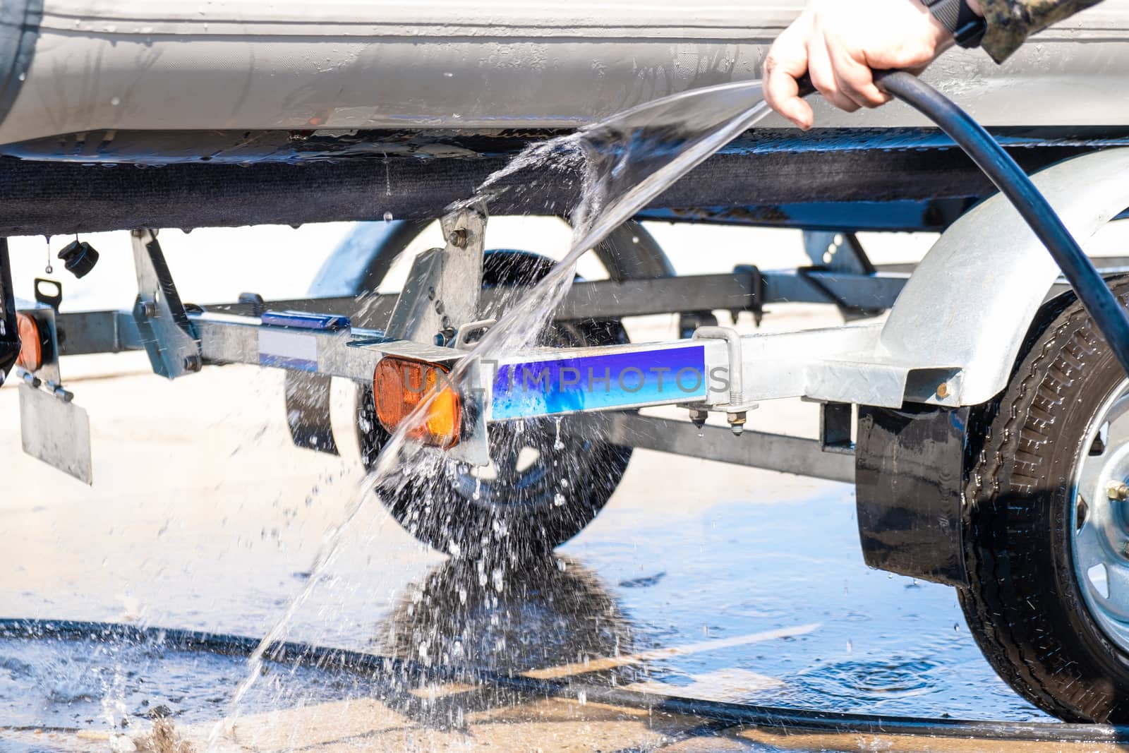 A man washes a rubber hose boat after going to sea. Drops of water scatter from the boat.