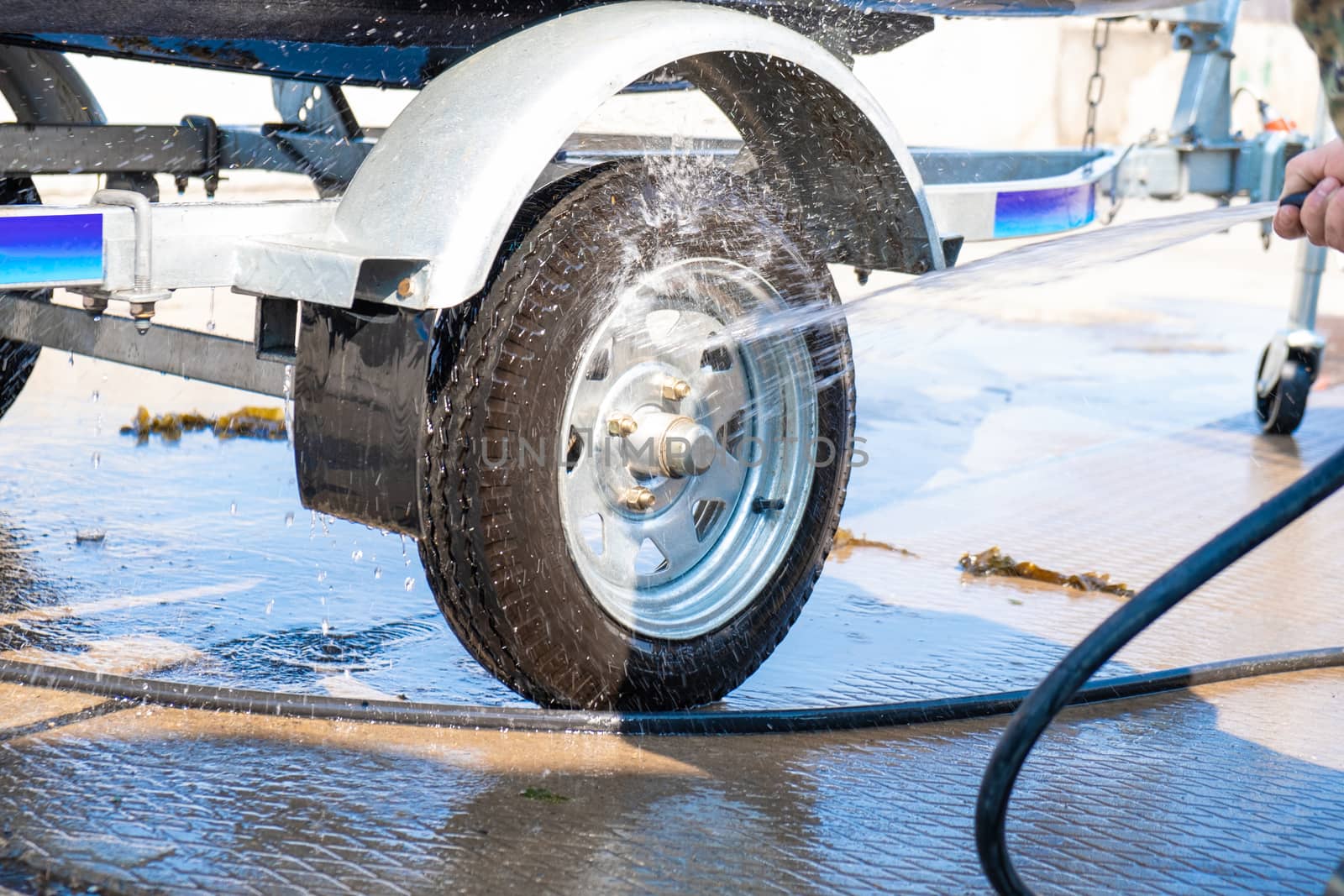 A man washes a rubber hose boat after going to sea. Drops of water scatter from the boat.