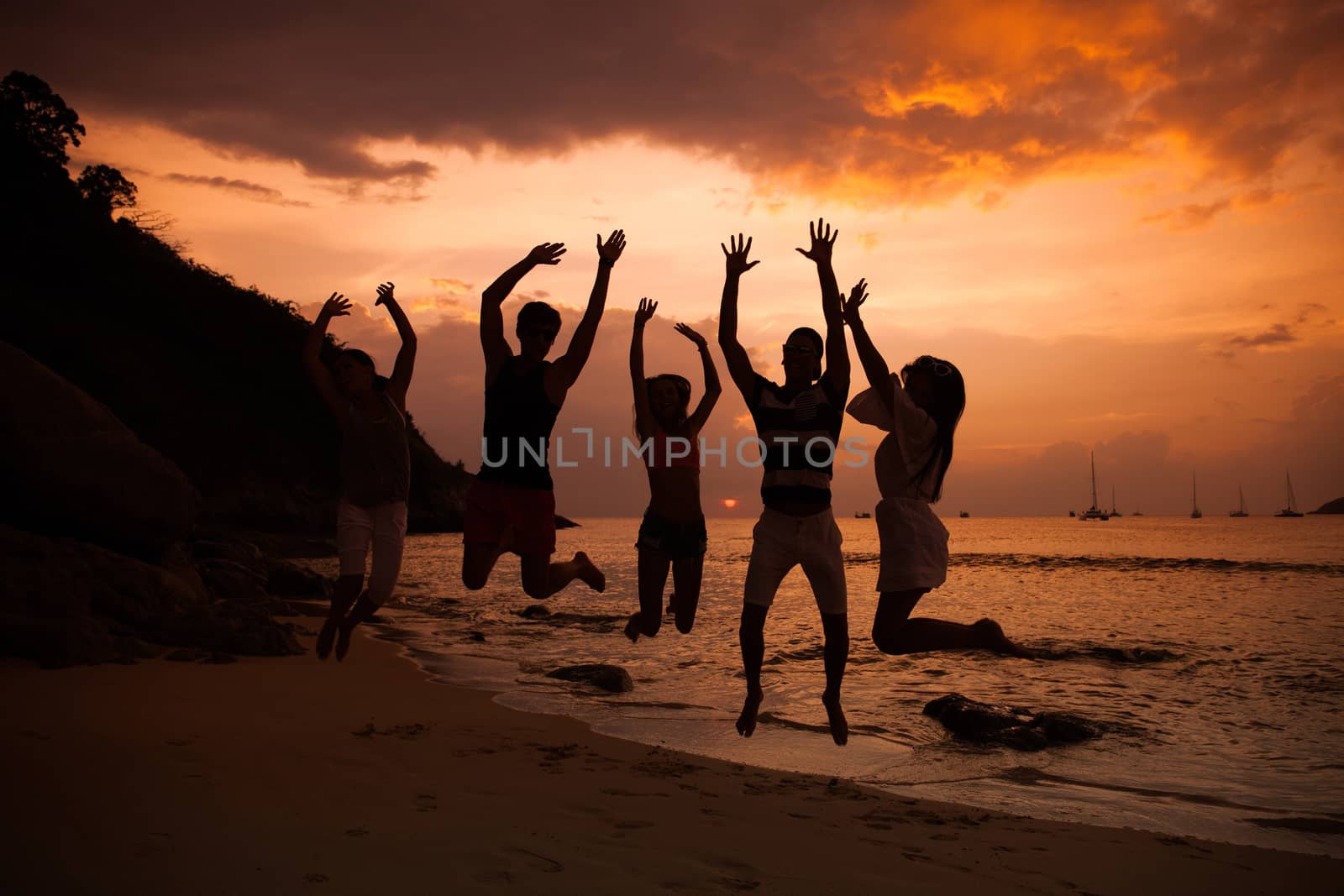 Group of happy people at sea beach at sunset