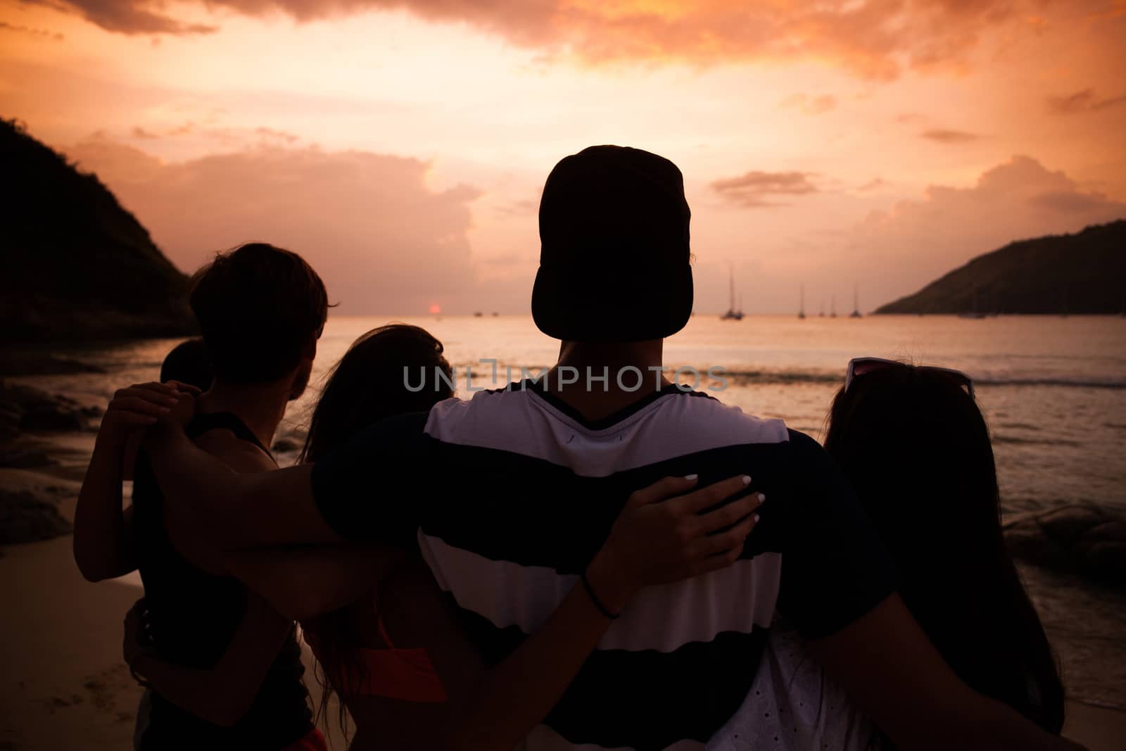 Group of happy people at sea beach at sunset