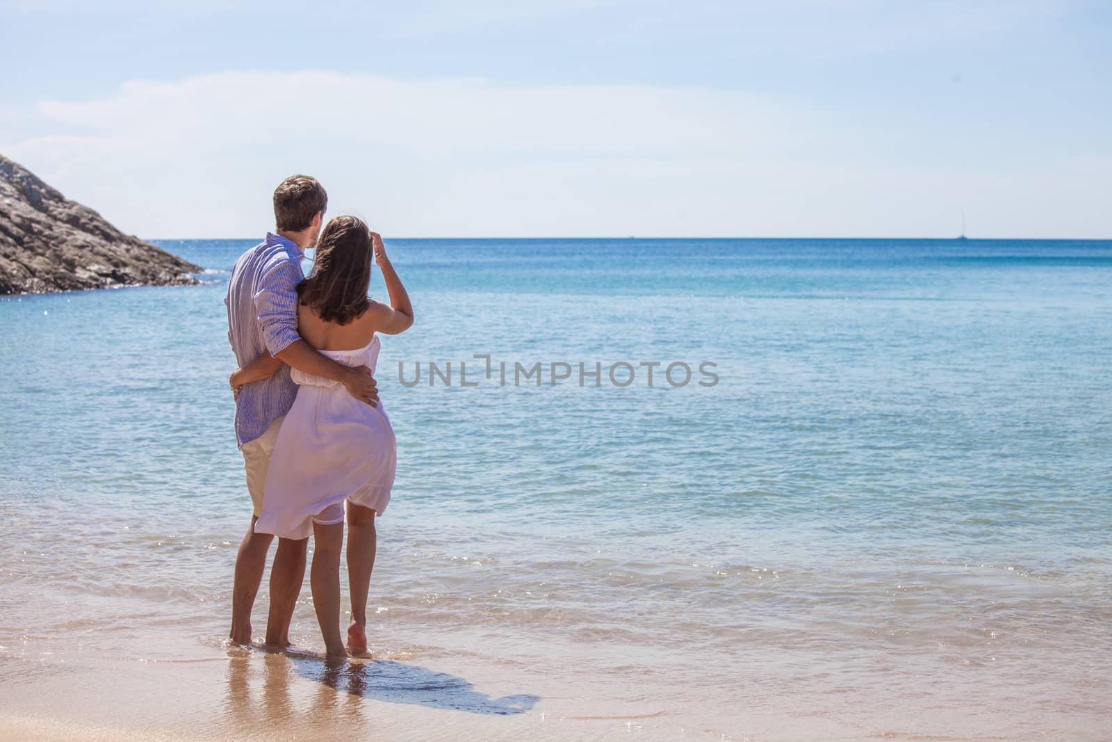 Young couple on beach looking at sea together