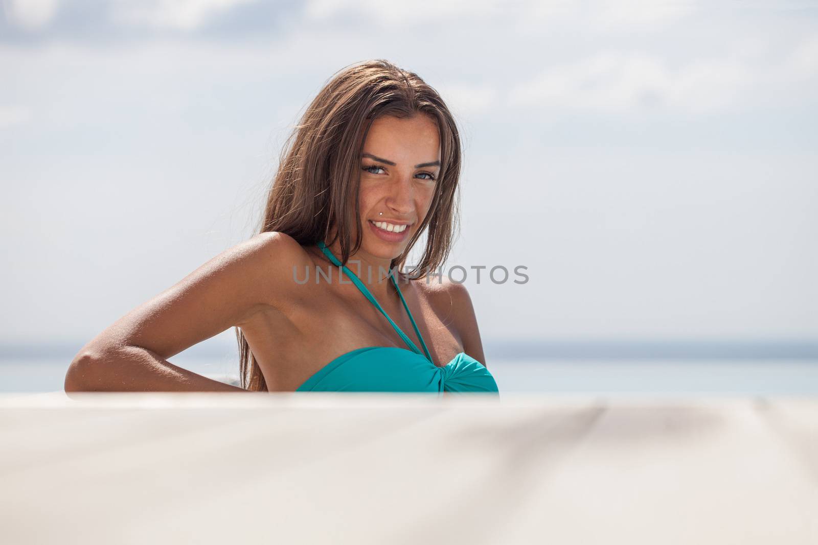 Girl resting at the end of a stunning infinity pool. Sea on background