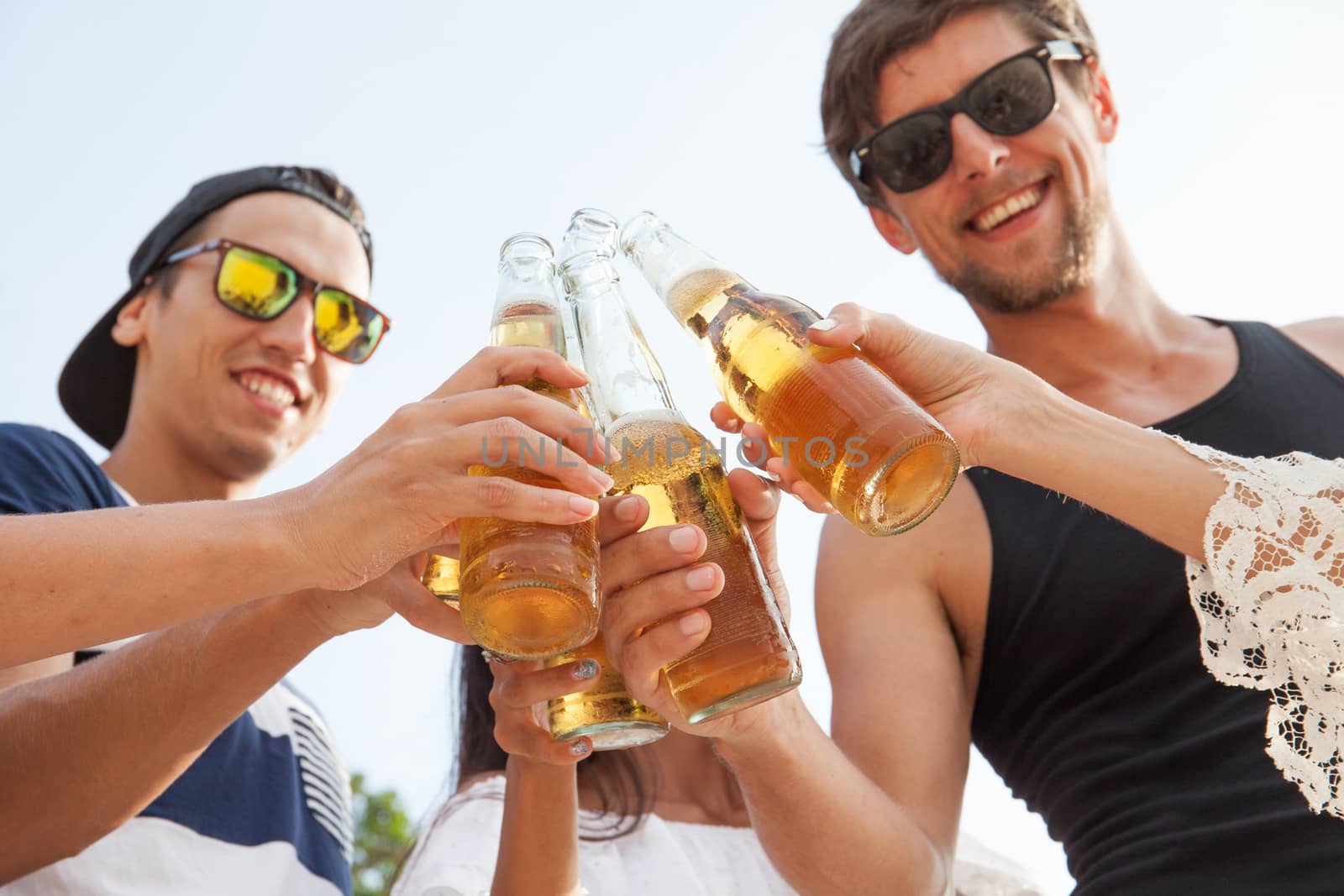 Happy young friends drinking beer outdoors