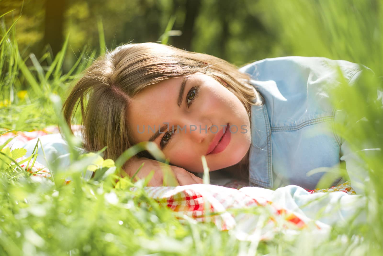 Beautiful young woman sleeping on fresh spring grass in park