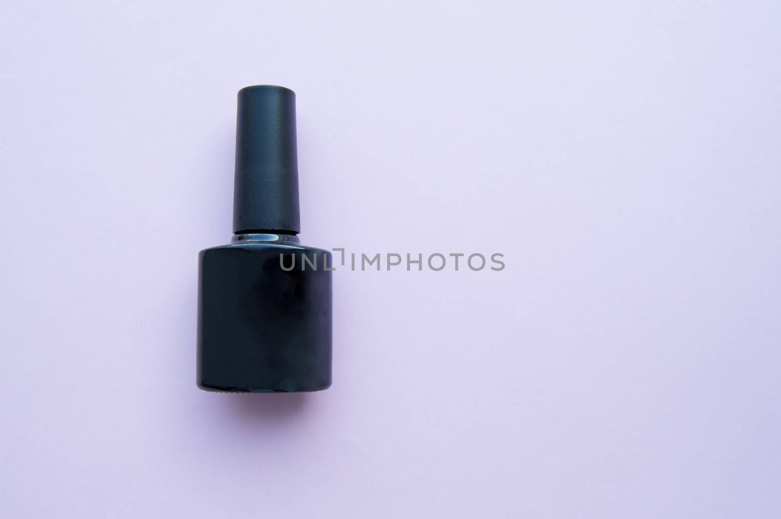 Pure black nail Polish bottle on lilac background, copy space, place for your text.