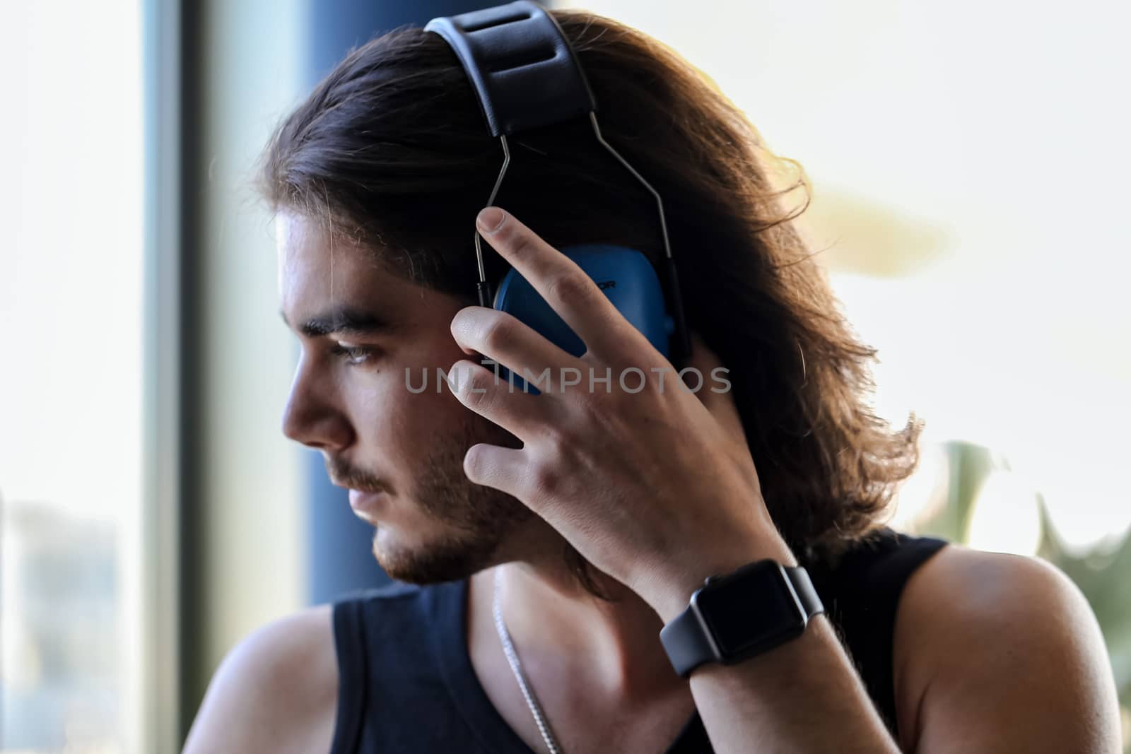 Young handsome brunette man puts on anti-noise headphones, preparing to fly a helicopter
