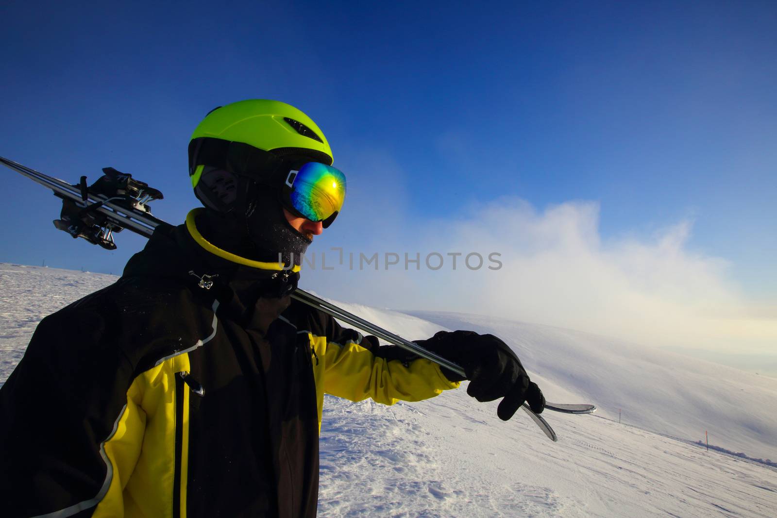 skier holding a pair of skis looking at the mountains