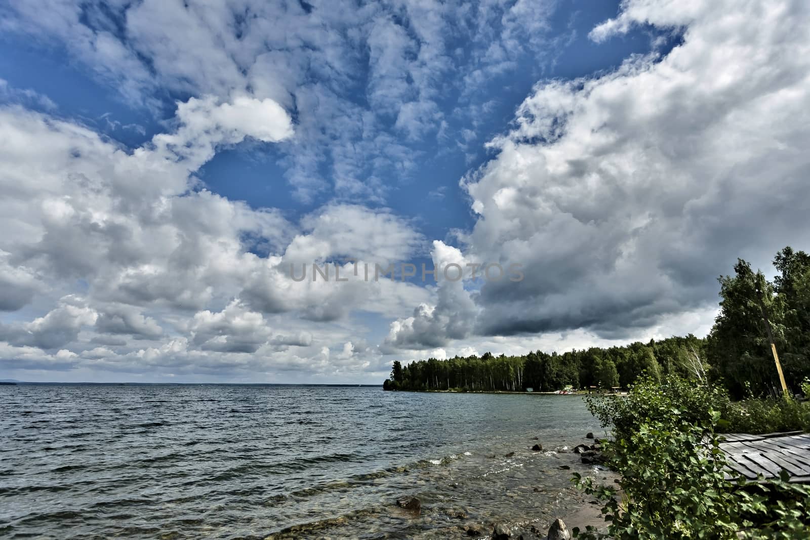 sky over the lake with cumulonimbus clouds illuminated by the sun, morning by valerypetr