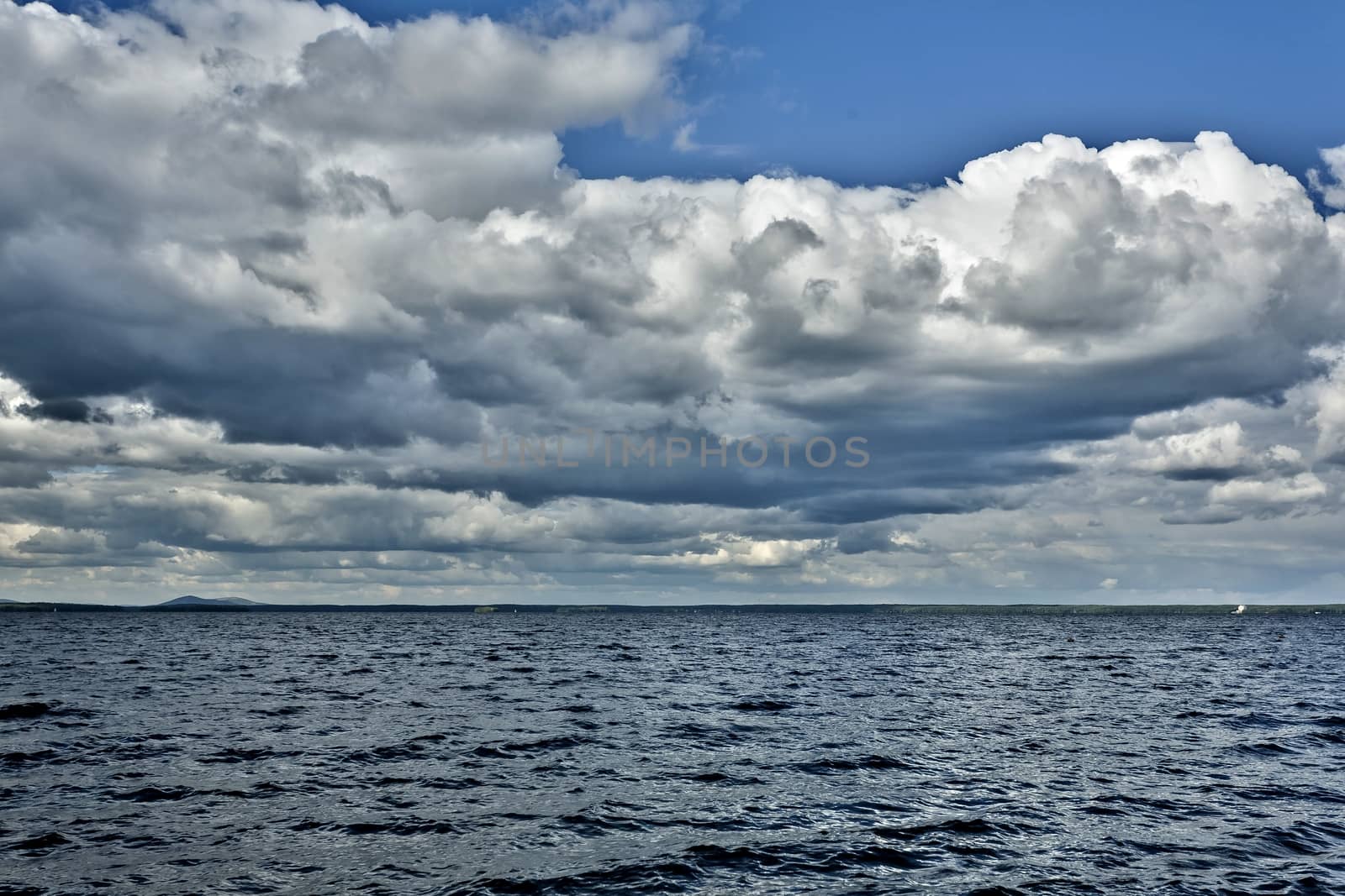 day lake in gray-white cloudy weather, South Ural, Uvildy, in the distance are seen the Ural mountains
