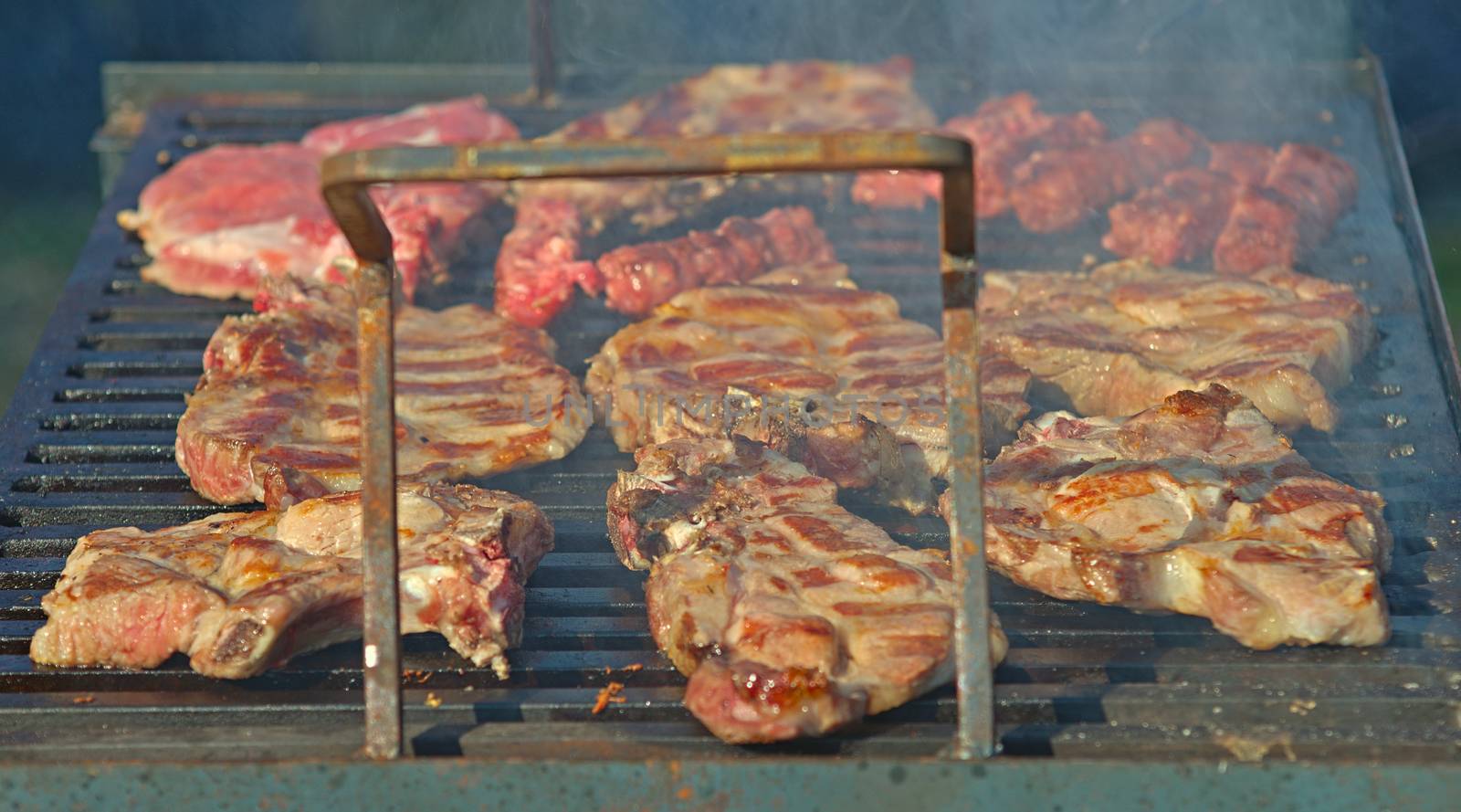 Pork chops roasting on barbeque grill with smoke around