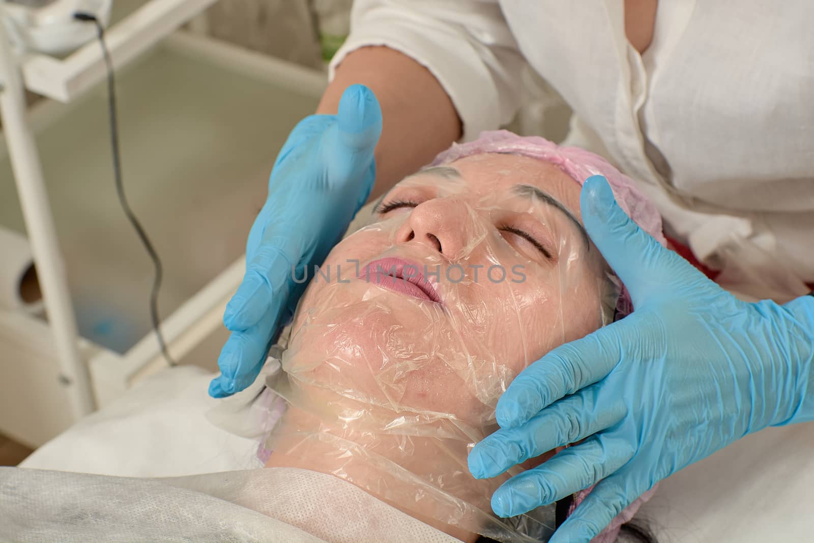 Young woman in beauty salon doing peeling and facial cleansing procedure. Cosmetic multifunctional device. Ultrasound procedure. Medical equipment healthcare. Face professional massage.