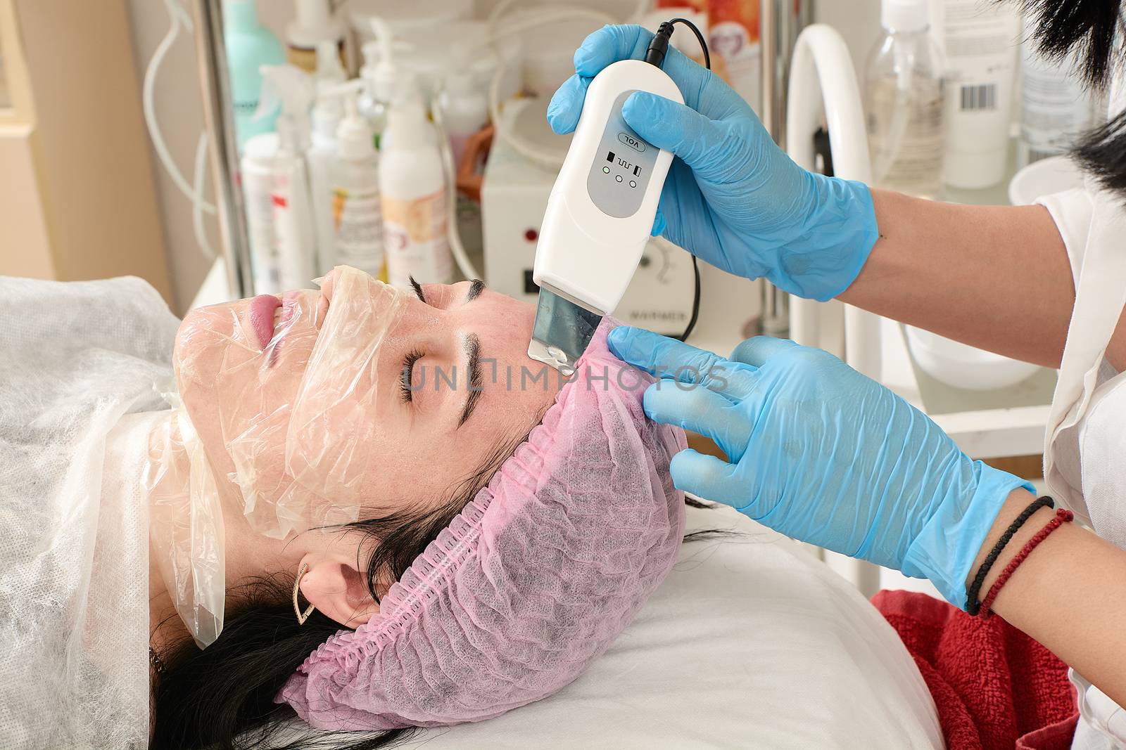 Young woman in beauty salon doing peeling and facial cleansing procedure. Cosmetic multifunctional device. Ultrasound procedure. Medical equipment healthcare. Face professional massage.