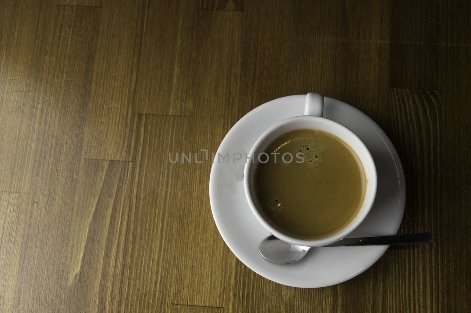 a cup of coffee and spoon placed on a brown table