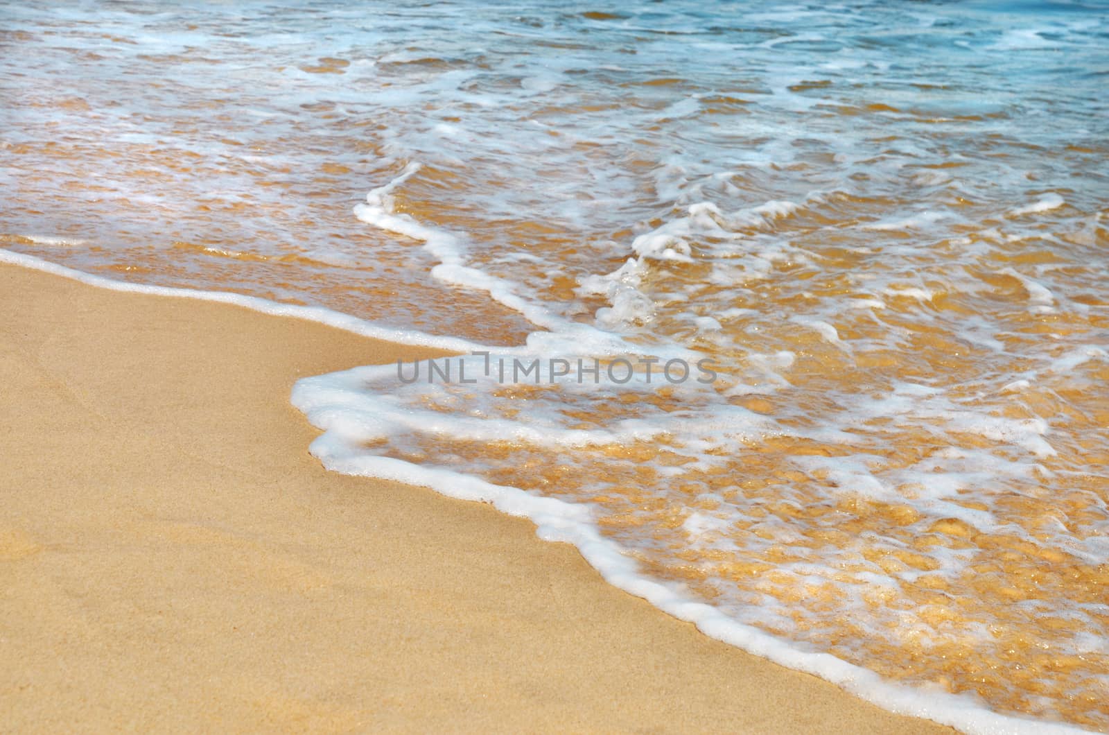 Summer holiday background. Small wave and foam, yellow, clean sandy beach.