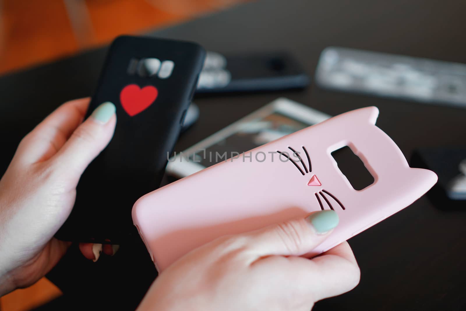 Hands holding colorful smartphone cases. Choose between a black and pink smartphone case