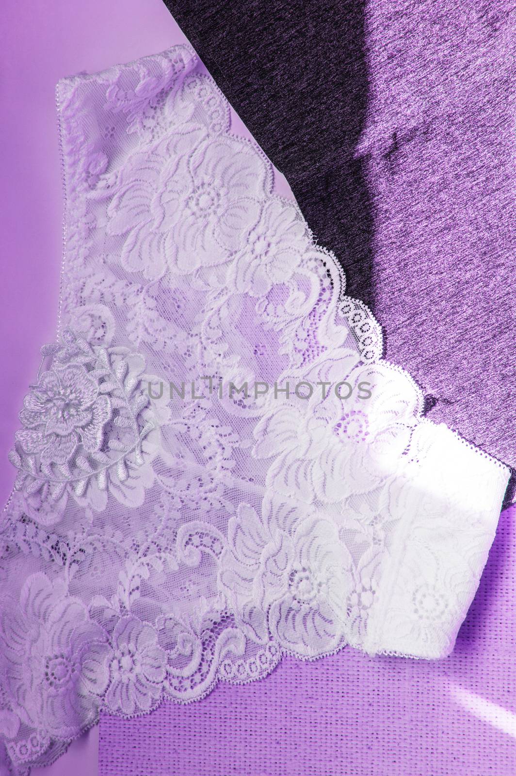 Lacy white sexy women's panties on purple neon background. Vertical shot, top view, flat lay by claire_lucia
