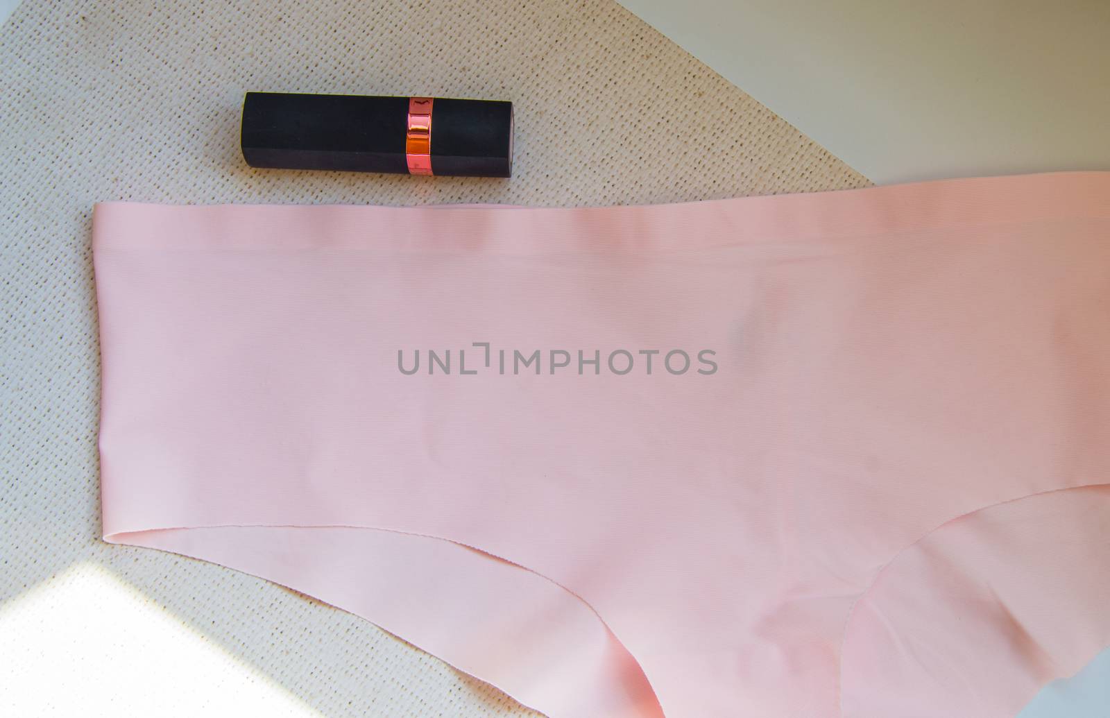Flat lay women's accessories - underwear and cosmetics.The view from the top women's pink bikini panties and lipstick. The concept of buying by claire_lucia