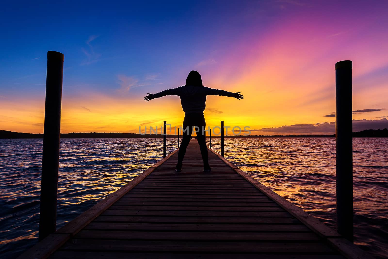 happy and relax woman, female, on wood bridge over sea or ocean near Copenhagen Denmark at awesome beautiful sunset time