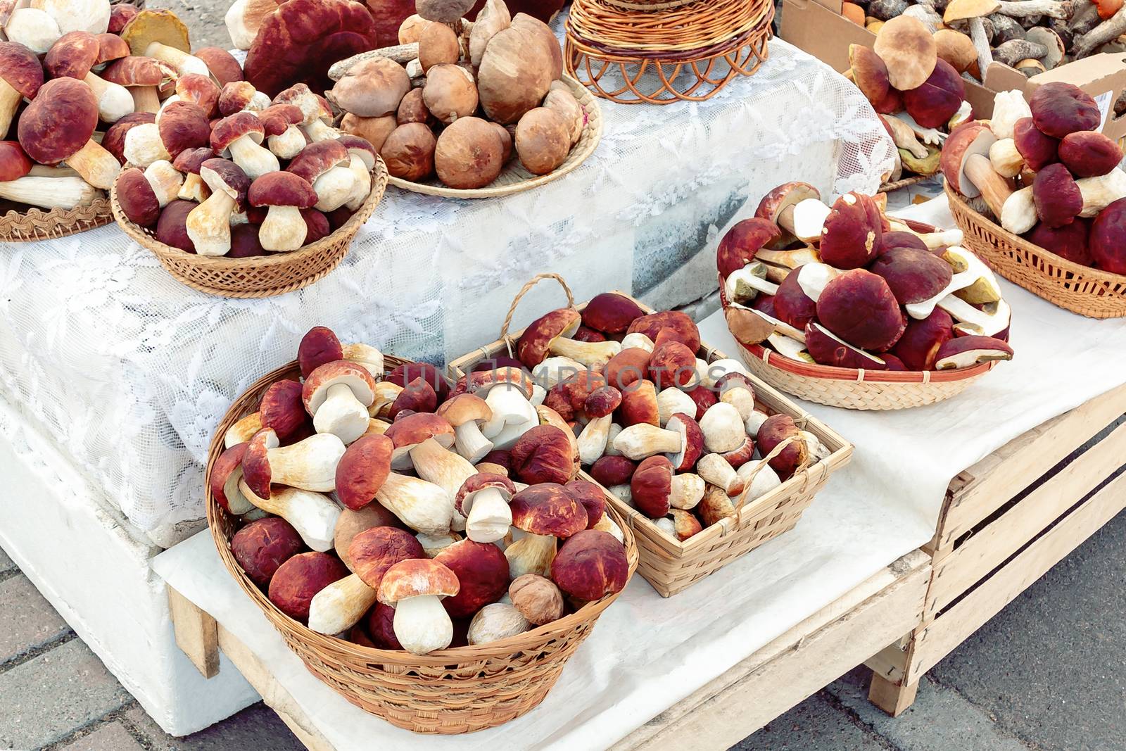 Many edible forest mushrooms boletus edulis f. pinophilus known as king bolete, penny bun and sep in wicker baskets laid out for sale on the market by galsand