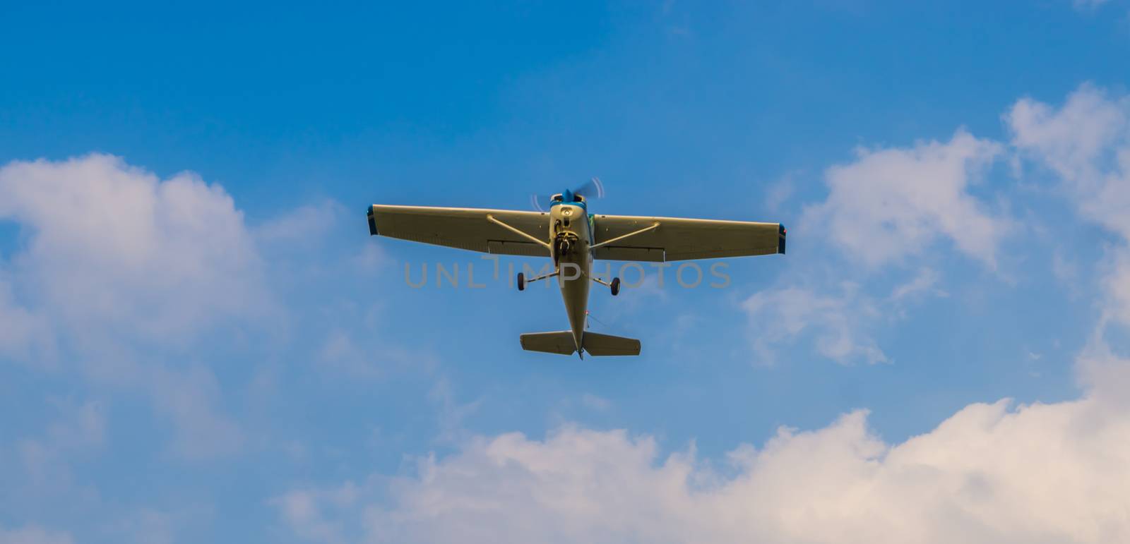 stunt airplane flying in a blue sky with clouds, air transportation, hobby and sports