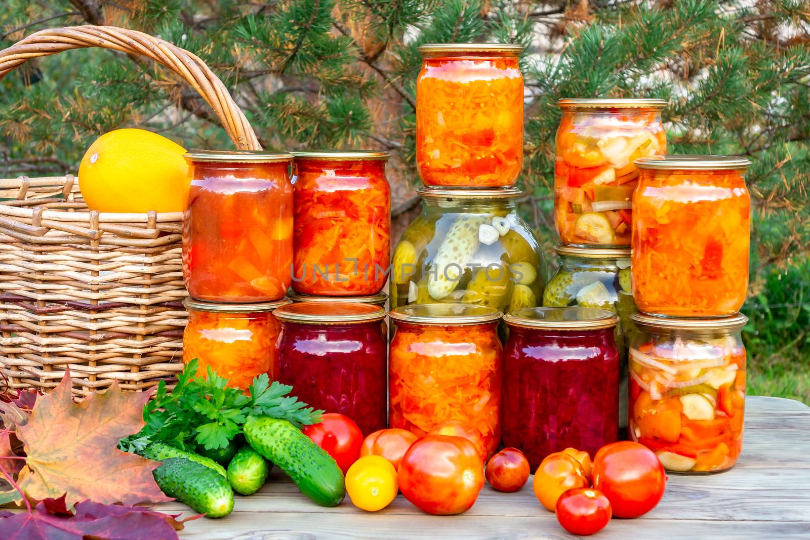 Several homemade jars of canned vegetables and fresh vegetables on a wooden table - image.